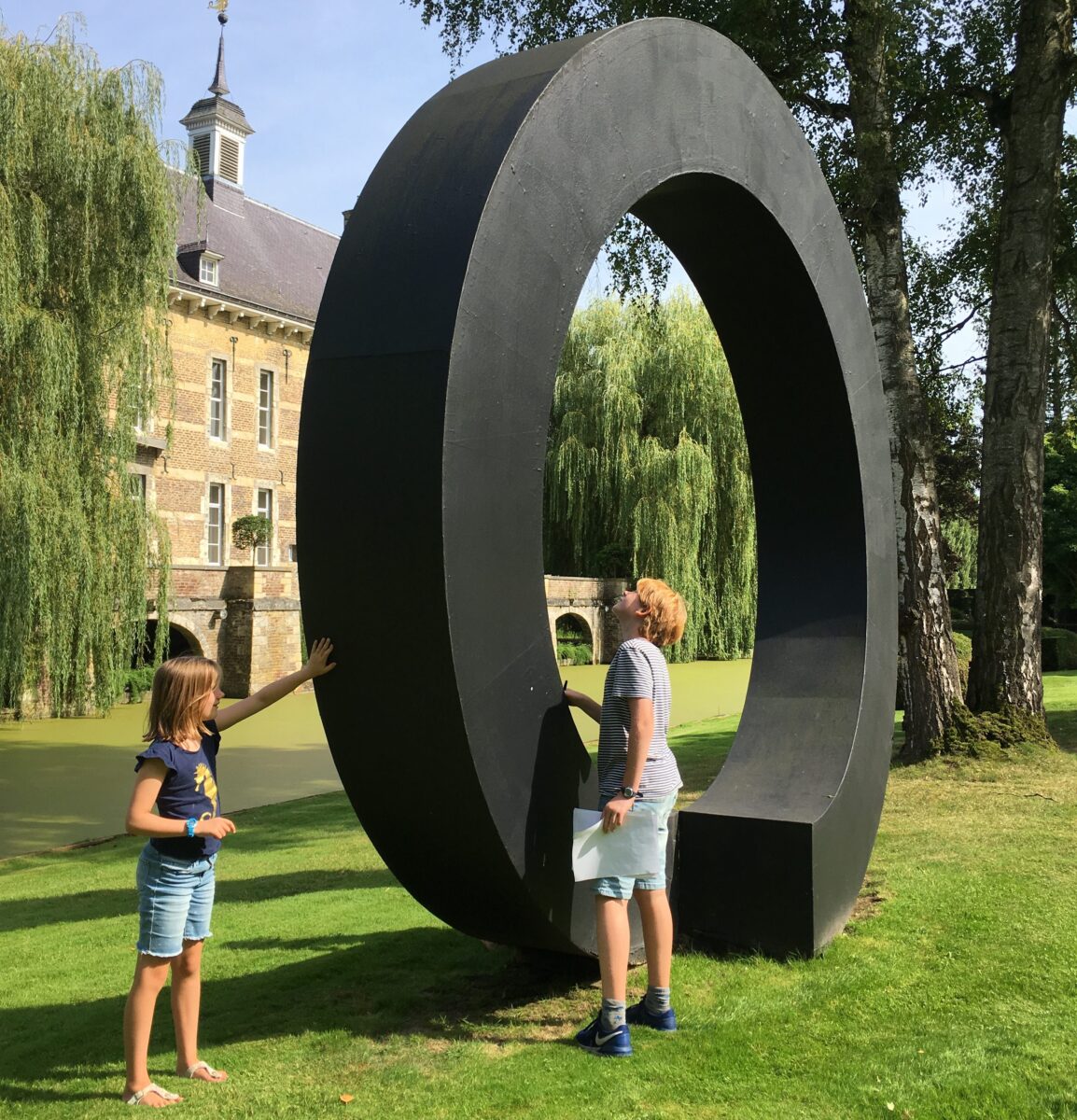 A boy and a girl look at Ad Dekkers' Broken Circle. This modern bronze sculpture stands on the lawn surrounding the Castle
